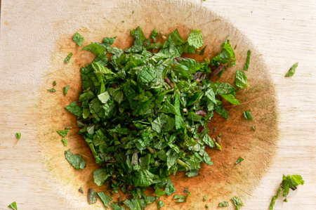 Mint has been finely chopped using a Mezzaluna double bladed knife on its chopping boardの写真素材