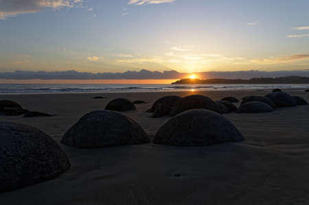 Moeraki Boulders are surrounded by water as the sun comes up. These calcite concretions were formed millions of years ago.の写真素材