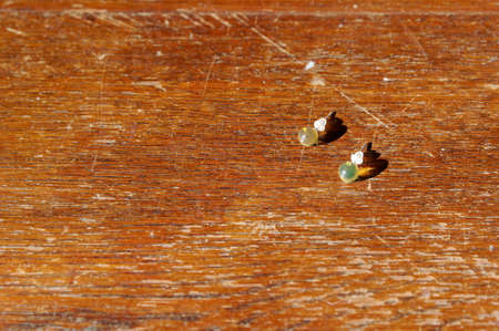 Two earrings are catching the sunlight, they have been left on top of a wooden cabinet.の写真素材