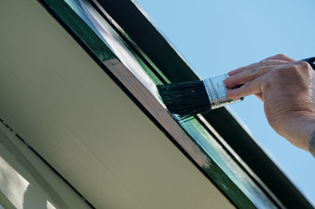 A top coat of paint is being applied to a barge board, the dark green will cover the pink undercoat...