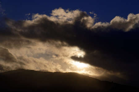 Hills are thrown into shadow by clouds moving across the sky and blocking out the sun.の写真素材