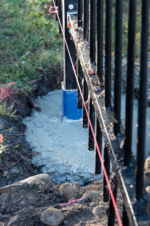 A line of pink builder's string has been run to ensure a fence panel is straight. The concrete holding the fence ost is still wet.の写真素材