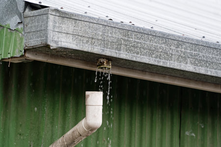 A down spout has come loose so the water it is meant to be catching is pouring out of the gutterの写真素材