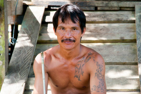 BORNEO, MALAYSIA - November 23, 2010: Local fisherman in Mulu sitting on his porchのeditorial素材