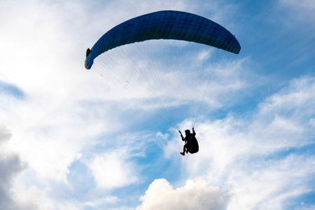Paraglider flying in the blue sky with white clouds.の写真素材