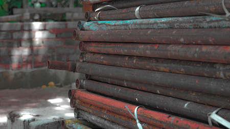 Steel pipes of different diameters lie in a pile on the streetの写真素材