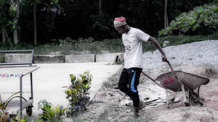 A man carrying a wheelbarrow on his shoulder in the street.の写真素材