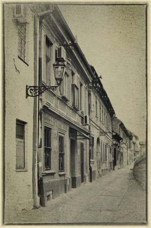 Street with old houses of the old town of Petrovaradin, near Novi Sad in Serbia. Black and white image stylized as vintage postcard.の写真素材