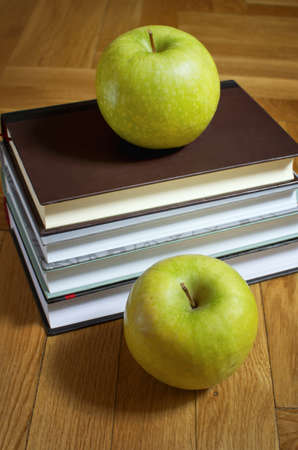Pile of books and two green apple on wooden background. Education concept.の写真素材