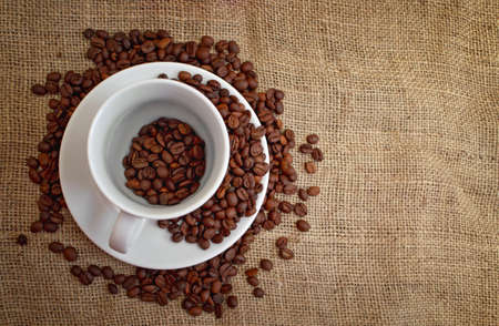 Cup with coffee beans on canvas backgroundの写真素材