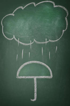 Hand drawn rain cloud with umbrella. Weather symbols on chalkboard.の写真素材