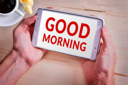 Good Morning on digital tablet with croissant and cup of coffeeの写真素材