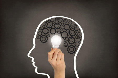 Light bulb on human head shaped on blackboard
