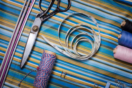 Sewing accessories - thread, scissors, needles, buttons, ribbons on the fabric. Tailoring concept.の写真素材