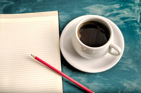 Open a blank white notebook, pencil and cup of coffee on the table