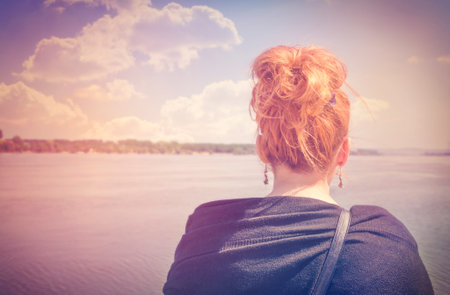 A woman looking at the river during a nice sunny spring morningの写真素材