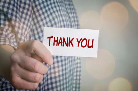 Man wearing plaid shirt and showing Thank You card. Blurred bokeh background.の写真素材