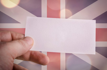 Hand holding a blank business card with the British flag and bokeh lights in the backgroundの写真素材
