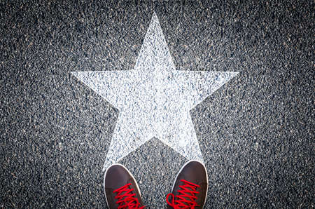 Sneakers on asphalt road with white starの写真素材