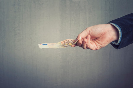 Businessman`s hand holding a 5o euro banknote. Paying, buying or selling concept.