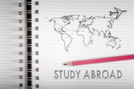 Study abroad. Airplane flying above world map pencil sketch on a notebook.の写真素材