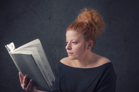 Serious young, beautiful girl holding an open book, read