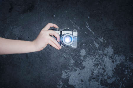 Male hand holding retro photo camera on the gray wall backgroundの写真素材
