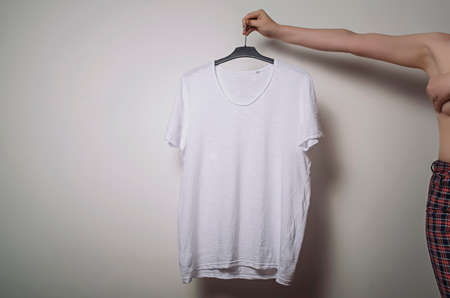 Girl with naked torso holding a white T-shirt in her hand. Branding Mock-Up.の写真素材
