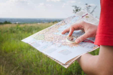 Detail of young tourist hands holds a map of Greece and compass with the sea and sky in the background. Travel guide, tourism in Europe.の写真素材