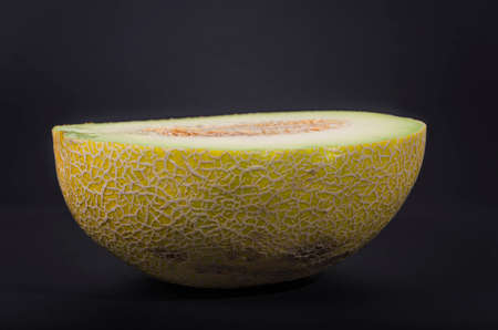 Half ripe yellow melon on a dark background.の写真素材