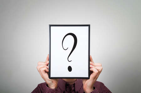 Businessman is covering his face with a question mark. Uncertainty and dilemmas concept.の写真素材