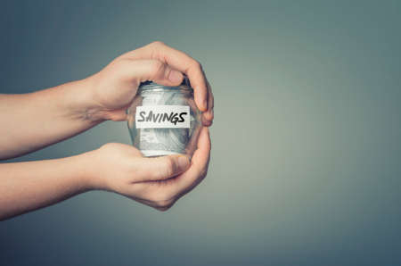 Man hands with glass jar full of US dollars. Saving money concept.の写真素材