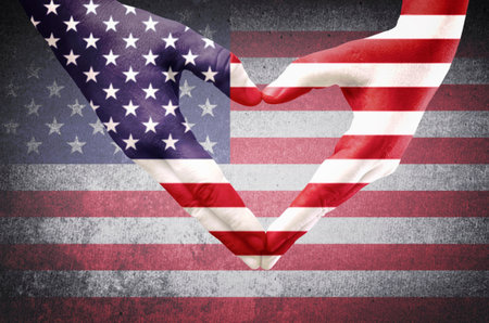 Hands of a young man forming a heart patterned with an American flagの写真素材
