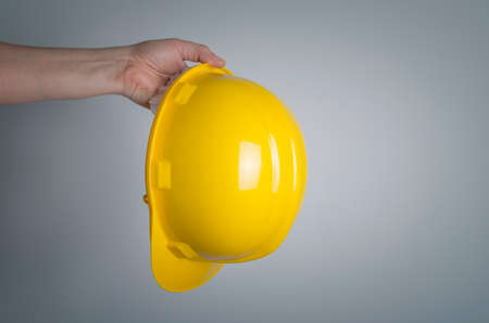 Yellow construction helmet in hand. Concept of protection and safety at work.の写真素材