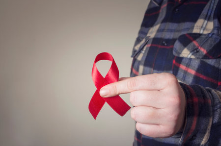 Aids Awareness. Male hands holding the red AIDS awareness ribbon. Healthcare and medicine concept.