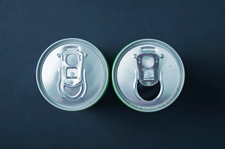 Cans. Top view of an unopened and opened metal can on dark background.