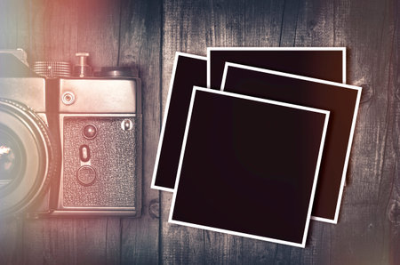 Vintage film camera detail with blank photo frames on wooden table. Top view.