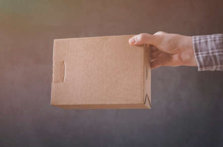 Man`s hand with carton box on dark background.の写真素材