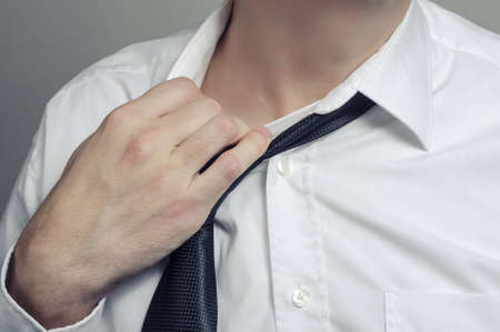 Man in white shirt taking off necktieの写真素材