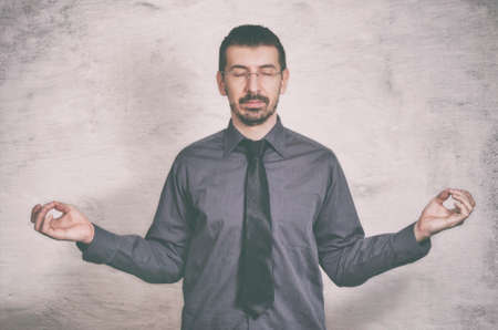 Young business man is meditating to relieve stress of busy corporate lifeの写真素材