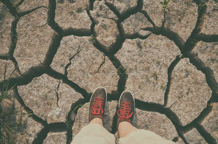 Sneakers standing on a dry cracked soil backgroundの写真素材