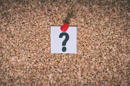 Close up of a question mark note pinned to a cork board. Concept for confusion question or solution.の写真素材