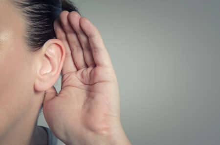 Woman with hand on ear listening for quiet sound or paying attentionの写真素材