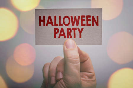 Halloween party card in hand with bokeh lights backgroundの写真素材