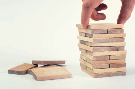 Businessman`s hand placing block on wooden tower. Business development concept.の写真素材