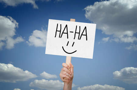 Ha-ha message on board in hand with sky background. Emotion Loud Laughter To Tears.の写真素材