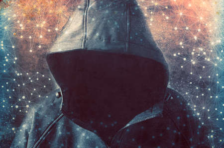 Unrecognizable hooded hacker. Concept of cyber crime, internet piracy and computer hacking.の写真素材