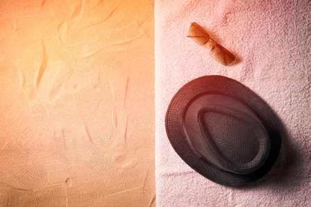 Summer background. Top view of sandy beach with towel frame, straw hat and sunglasses.