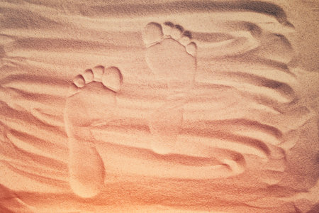 Human footprints on dry sand in sunset. Go forward. Top view.の写真素材