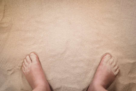 Bare human feet on a sandy beach. Sea background with copy space.の写真素材